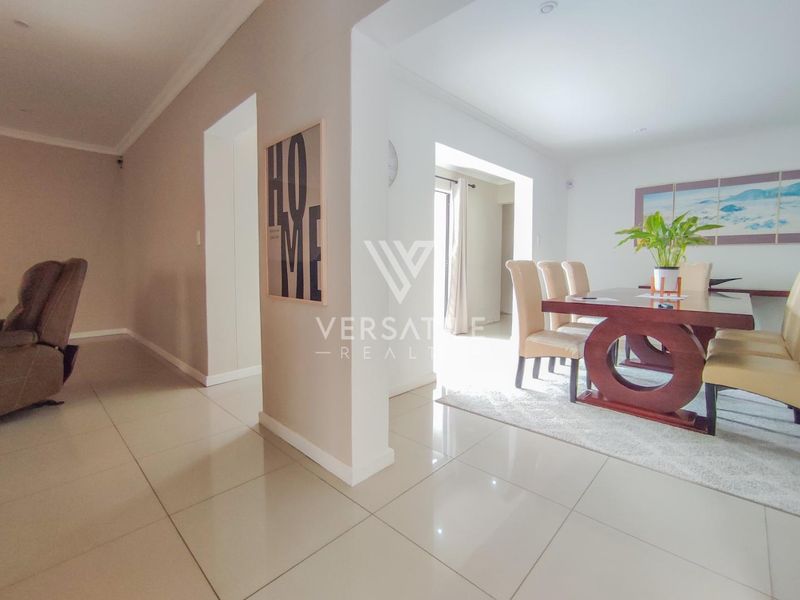 An open-plan living and dining area featuring neutral tiled flooring, recessed downlighting, and a clean, modern layout.