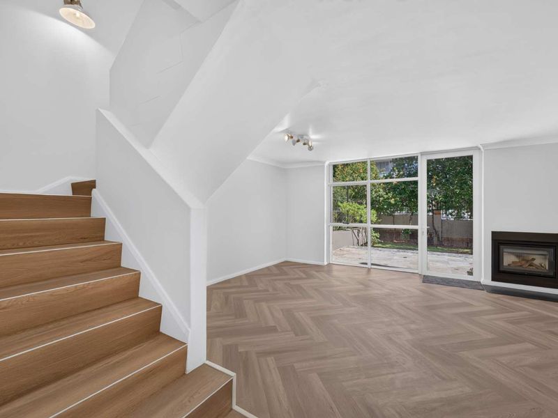 Bright and spacious living area featuring modern herringbone flooring, a built-in fireplace, and direct access to the outdoor patio through sliding glass doors.