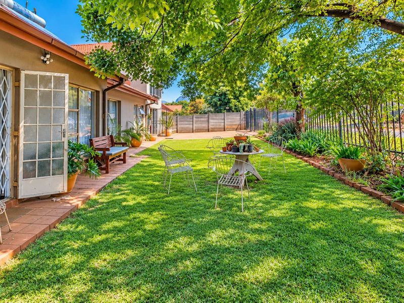 A well-maintained rear garden featuring a tiled patio area, lush lawn, and secure perimeter fencing, providing a pleasant outdoor space.