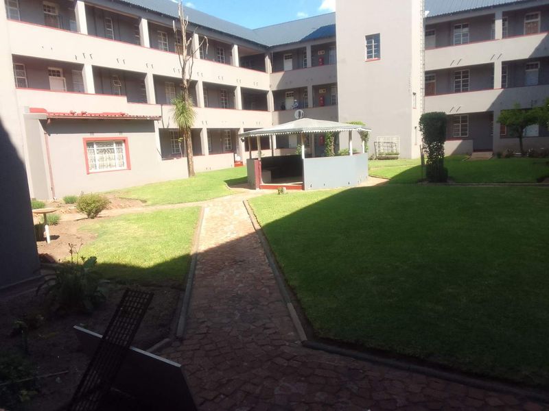 A view of the apartment complex courtyard featuring a central gazebo, paved pathways, and well-maintained lawn areas surrounded by multi-story residential units.