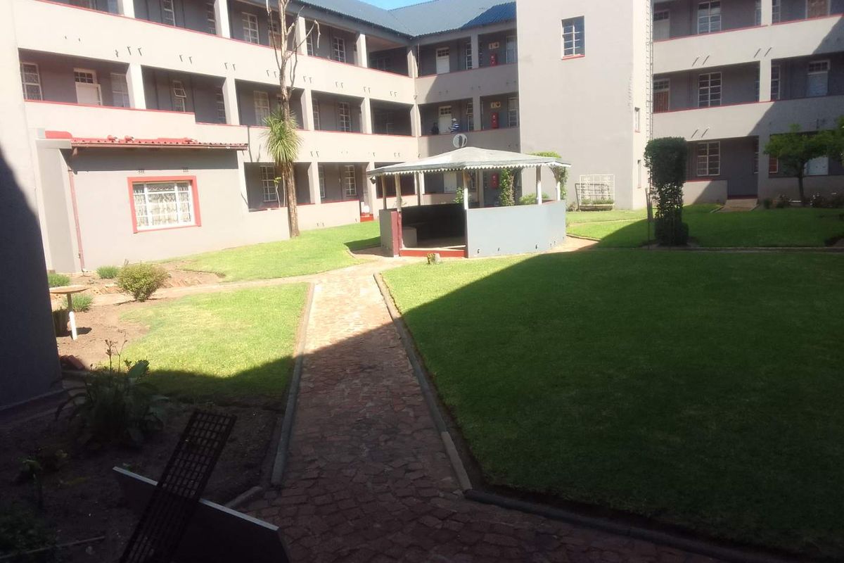 A view of the apartment complex courtyard featuring a central gazebo, paved pathways, and well-maintained lawn areas surrounded by multi-story residential units.