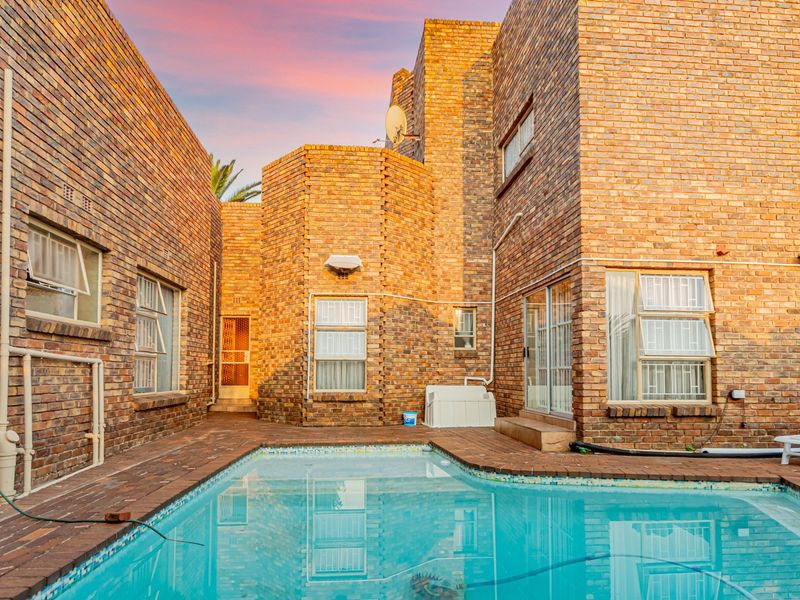 A private courtyard area featuring a swimming pool surrounded by facebrick walls and paved decking, providing a secluded outdoor space.