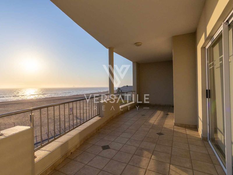 Spacious covered balcony featuring tiled flooring, a metal balustrade, and direct access to the interior via sliding glass doors, offering expansive ocean views.