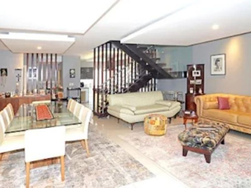 Spacious open-plan living and dining area featuring a modern staircase with glass balustrade and recessed ceiling details.