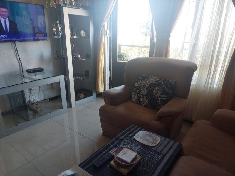A living room area featuring tiled flooring and a sliding glass door providing access to an outdoor space.