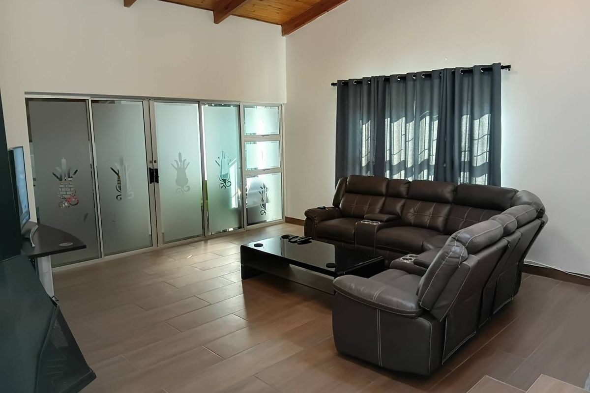 Spacious living room featuring exposed timber ceiling beams, tiled flooring, and large frosted glass sliding doors providing natural light.