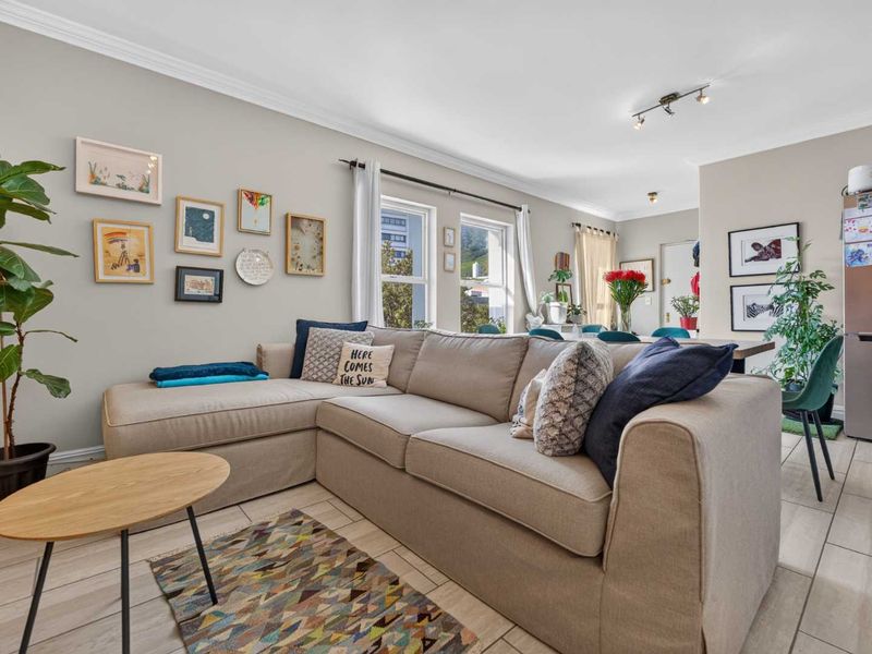 Bright open-plan living and dining area featuring neutral walls, tiled flooring, and modern track lighting, creating a comfortable and inviting space.
