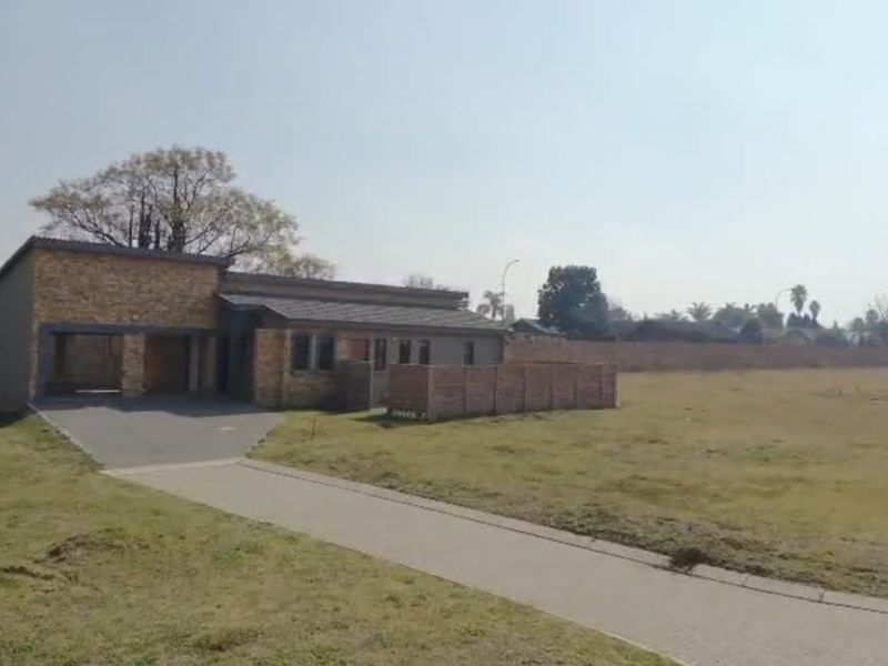 Front view of a residential property featuring a brick facade, paved driveway, and a covered carport on a spacious plot.