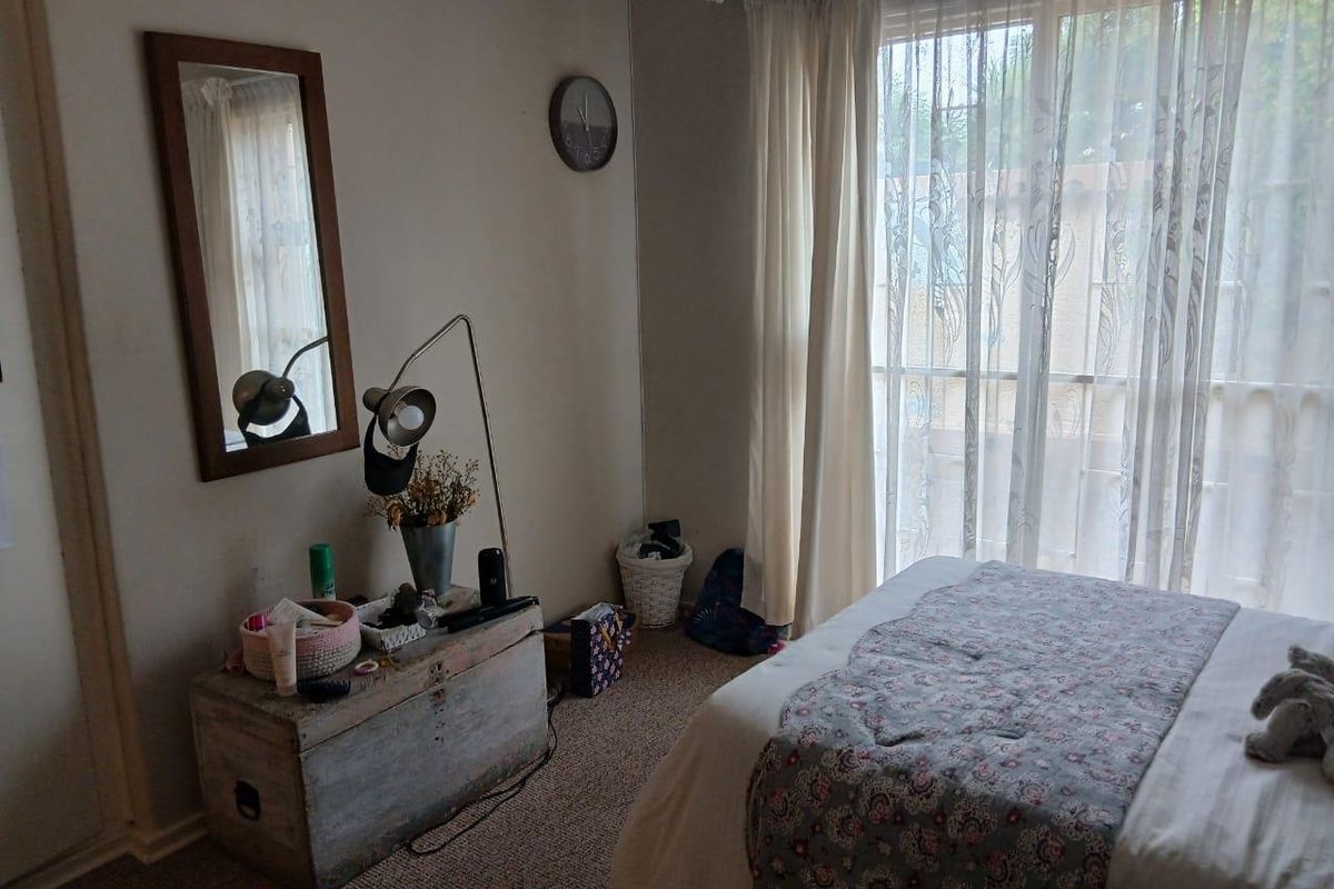 A bedroom featuring carpeted flooring and a sliding glass door with curtains providing natural light.