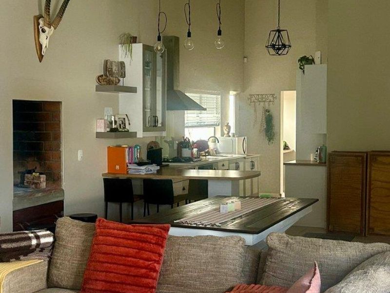 Spacious open-plan living area featuring a built-in fireplace, high ceilings with exposed beams, and a functional kitchen with a central island.
