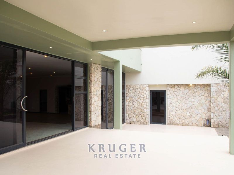 A spacious covered patio featuring stone cladding accents and large sliding glass doors providing seamless access to the interior living area.