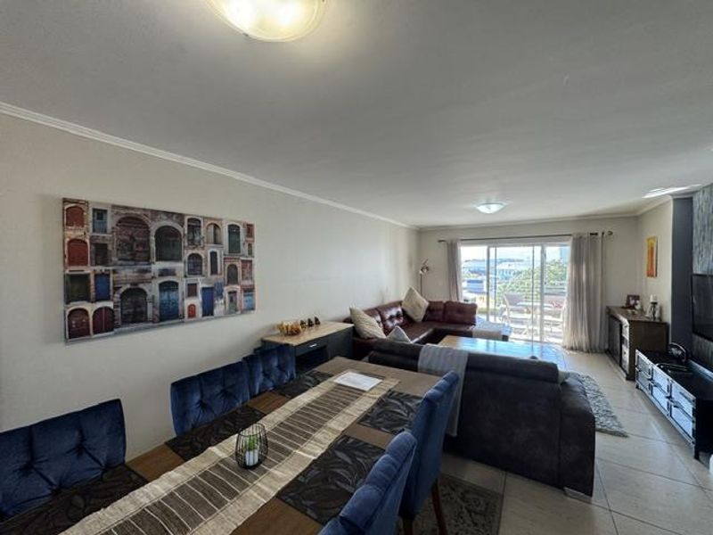 Spacious open-plan living and dining area featuring tiled flooring and large sliding glass doors leading to an outdoor balcony.