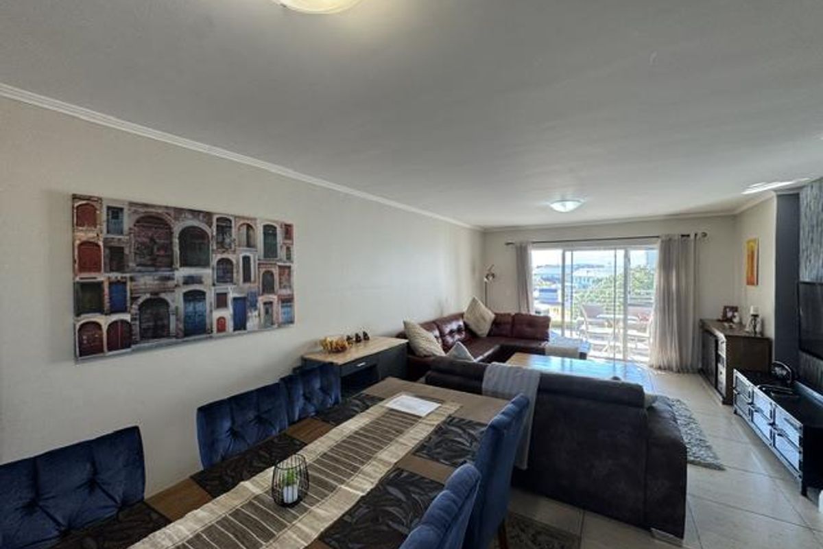 Spacious open-plan living and dining area featuring tiled flooring and large sliding glass doors leading to an outdoor balcony.