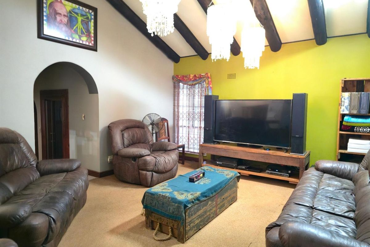 Spacious living room featuring a vaulted ceiling with exposed timber beams and a distinctive arched entryway.