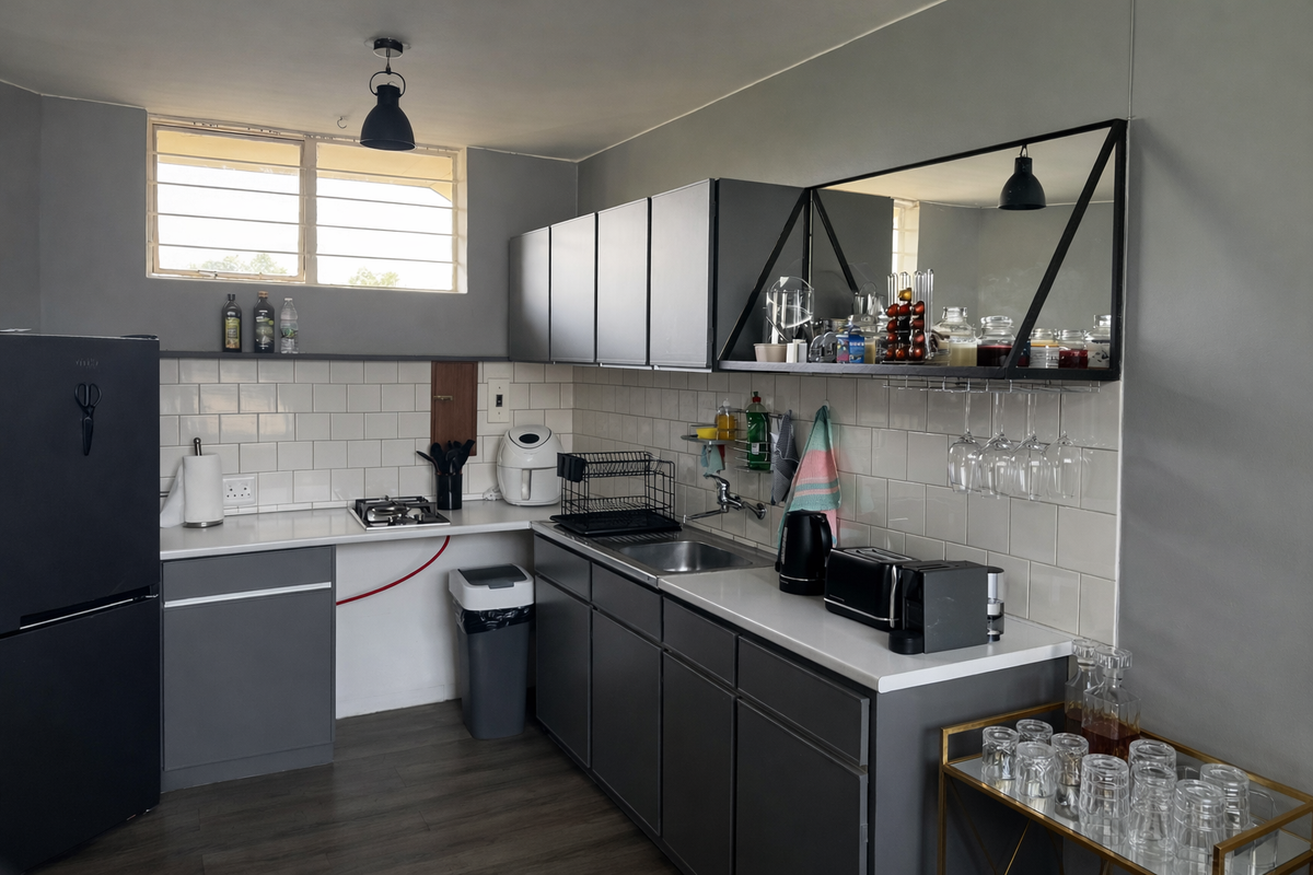 Compact kitchen featuring grey cabinetry, white subway tile backsplash, stainless steel sink, and a built-in gas cooktop with modern industrial-style shelving.