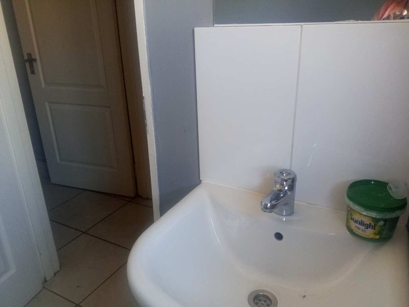A functional bathroom space featuring a white ceramic basin with a chrome mixer tap and tiled splashback.