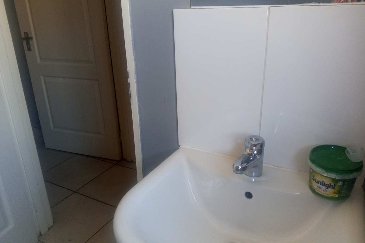 A functional bathroom space featuring a white ceramic basin with a chrome mixer tap and tiled splashback.