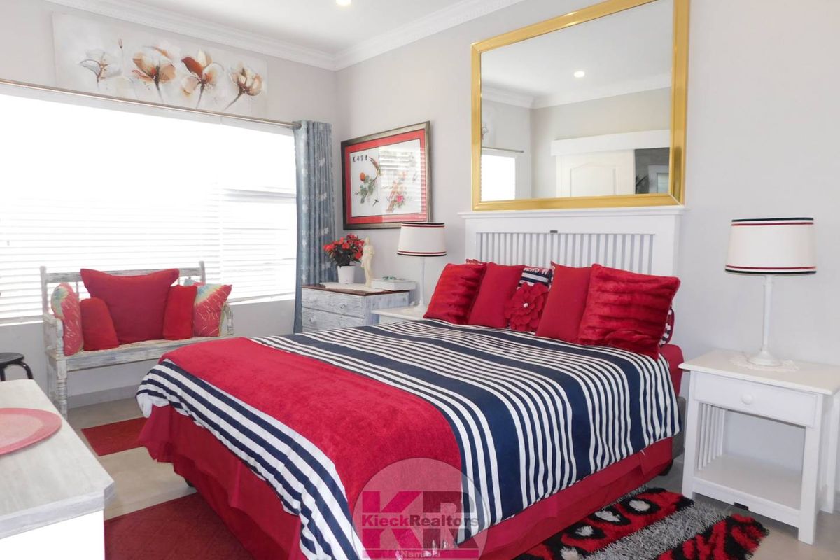 A well-maintained bedroom featuring crown molding, recessed lighting, and a large wall-mounted mirror above the bed area.