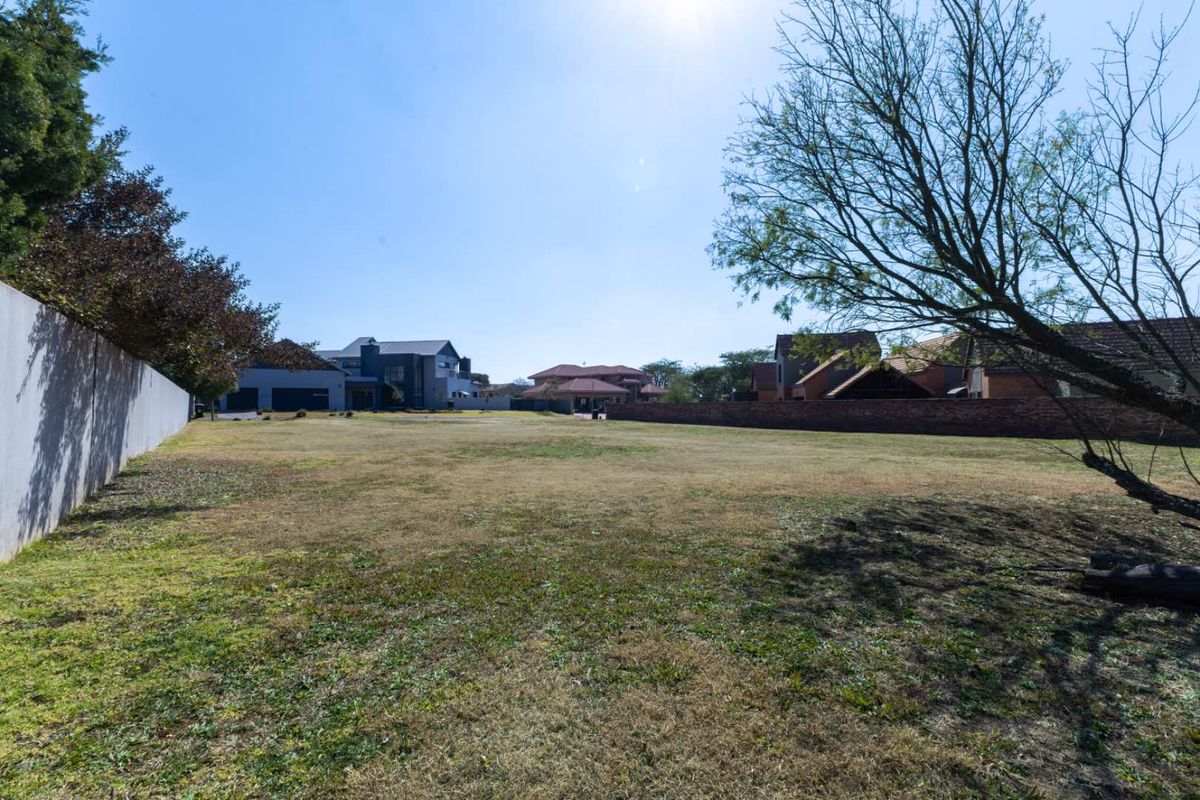 A spacious, level vacant residential plot featuring established perimeter boundary walls and mature trees, situated within a developed residential neighbourhood.