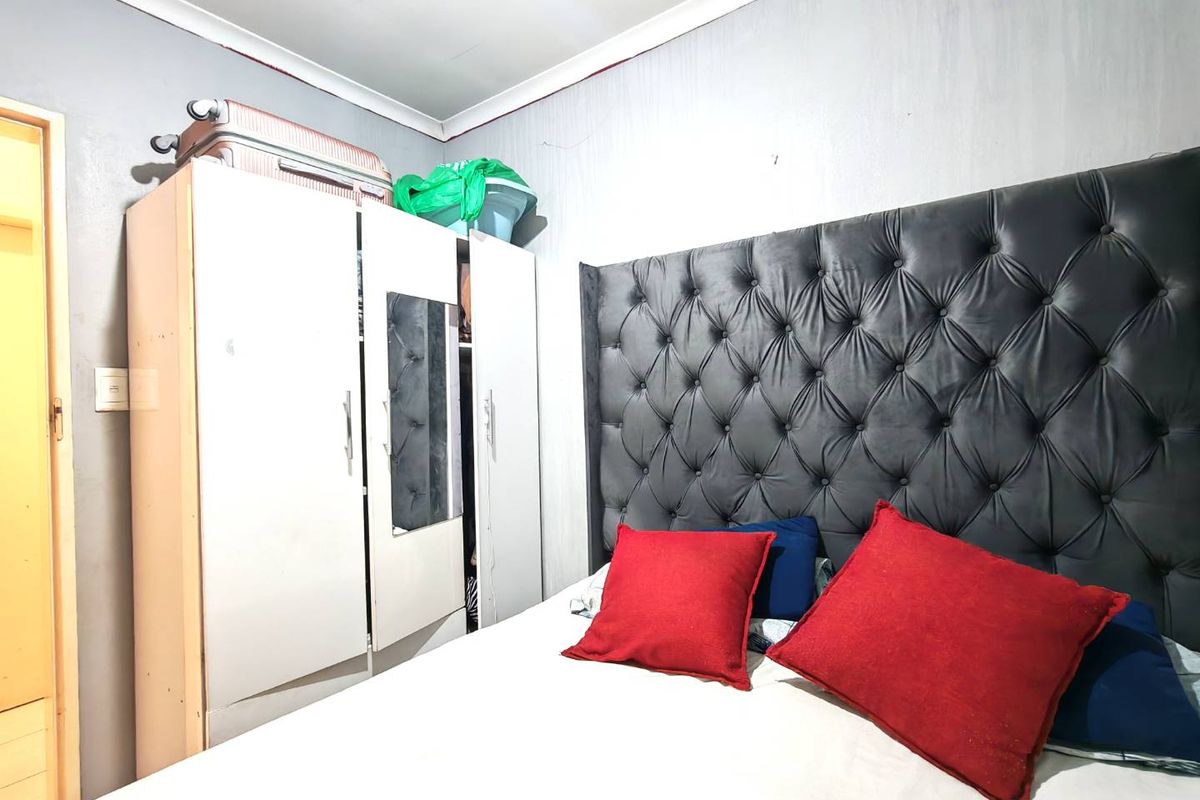A bedroom featuring a tufted headboard and built-in wardrobe storage.