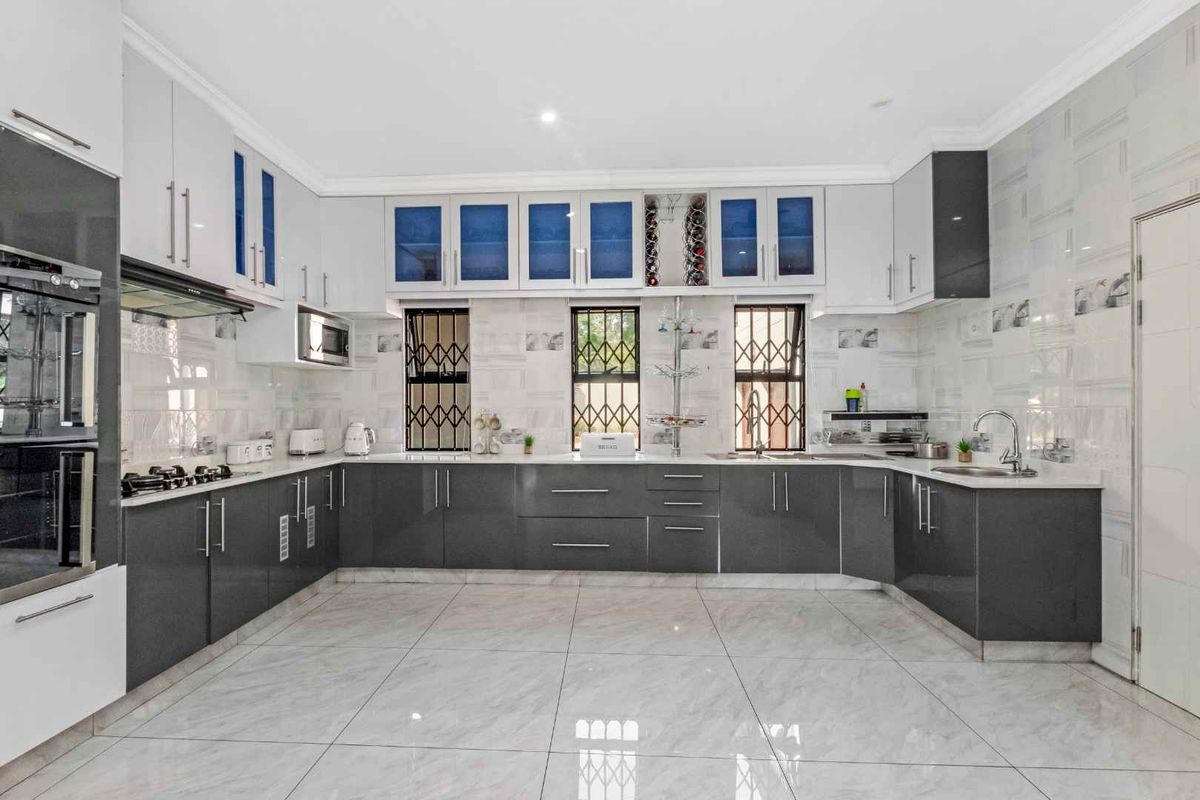 Modern kitchen featuring high-gloss cabinetry, stone countertops, integrated oven, gas hob, and tiled flooring with a clean, contemporary finish.