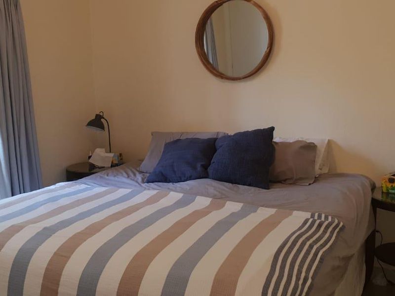 A comfortable bedroom featuring neutral walls and classic french doors that provide natural light and access to the outdoors.