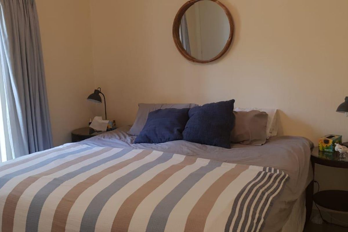 A comfortable bedroom featuring neutral walls and classic french doors that provide natural light and access to the outdoors.