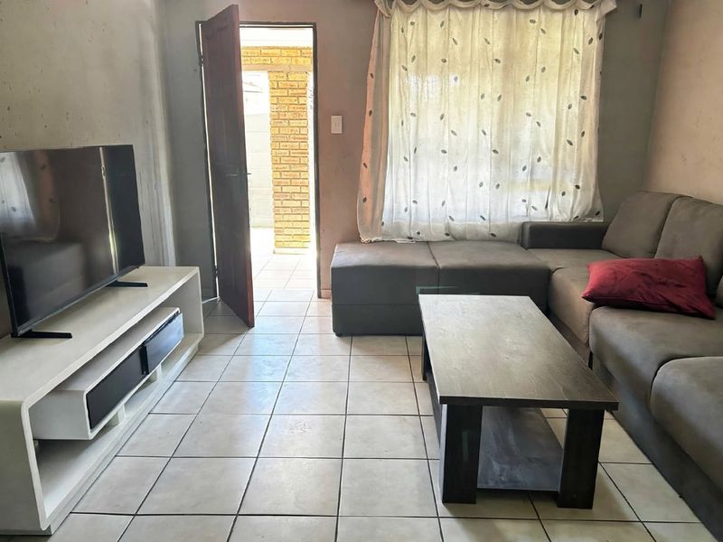 A living room featuring tiled flooring and direct access to an outdoor area, providing a functional space with potential for cosmetic updates.