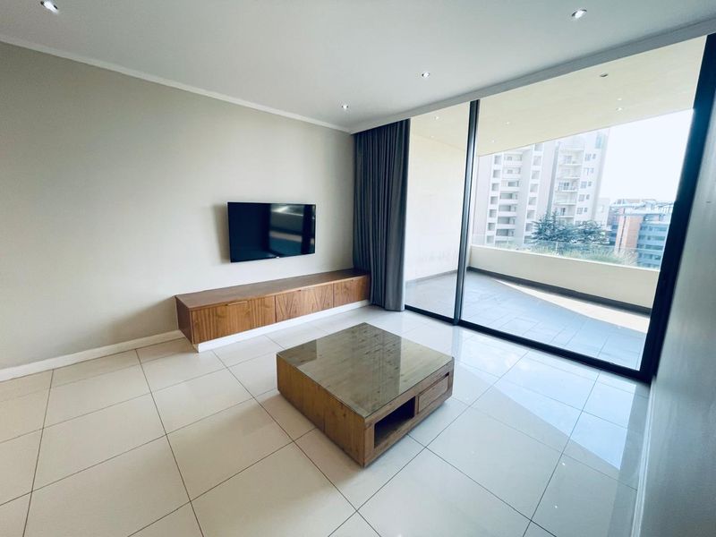 Modern living room featuring large sliding glass doors leading to a balcony, tiled flooring, recessed lighting, and a built-in media console.