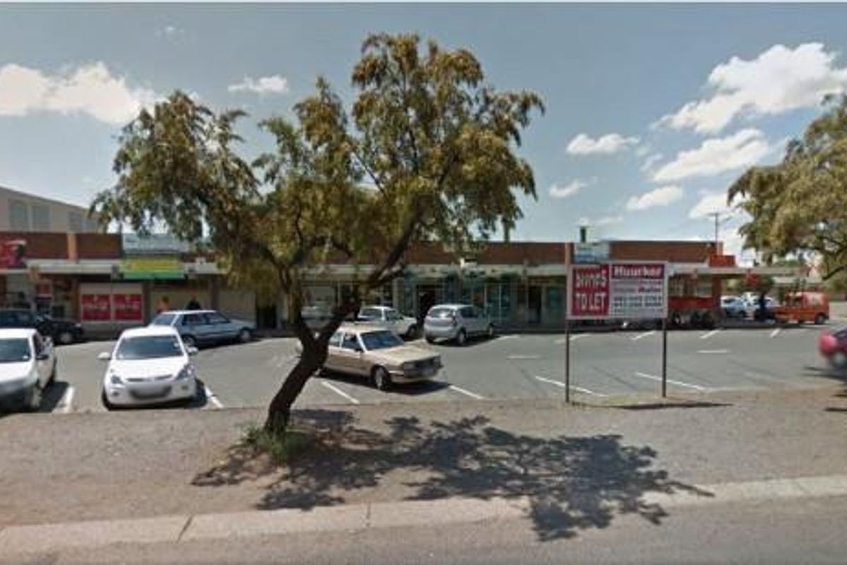 Street-level view of a commercial retail strip center with a paved parking lot and storefront access.
