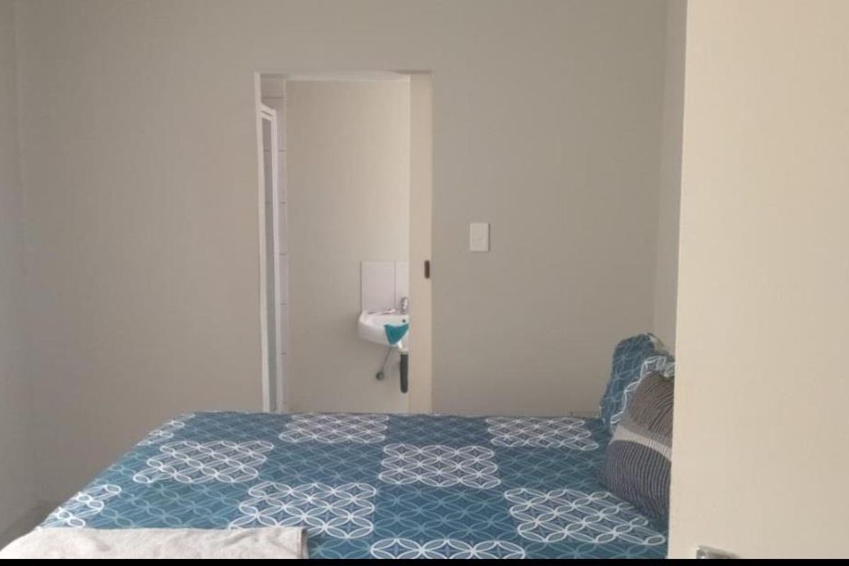 A bedroom featuring neutral wall tones with an adjoining en-suite bathroom visible through the doorway.