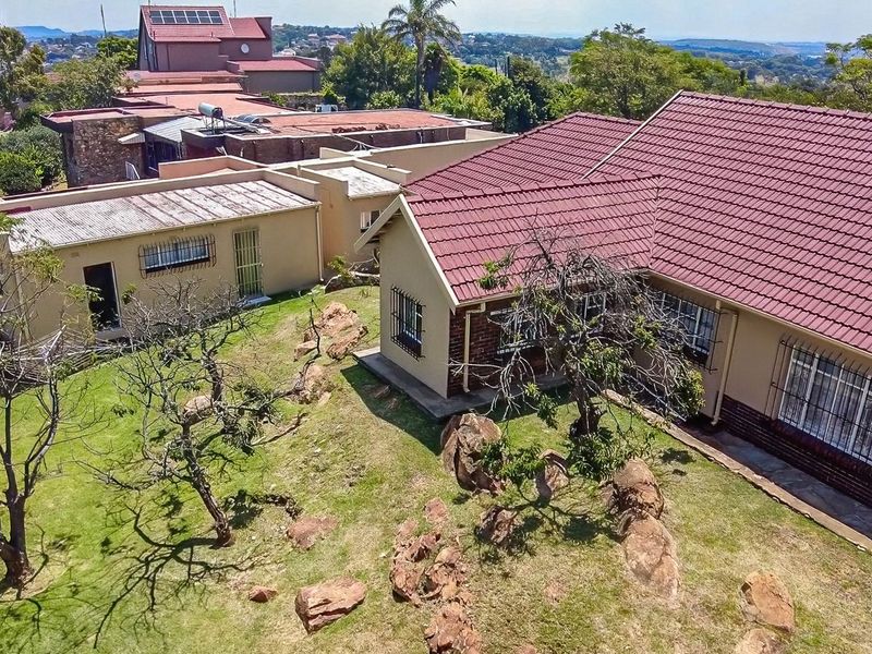 Aerial view of the property showcasing the tiled roof, brick exterior, security features, and surrounding garden area.
