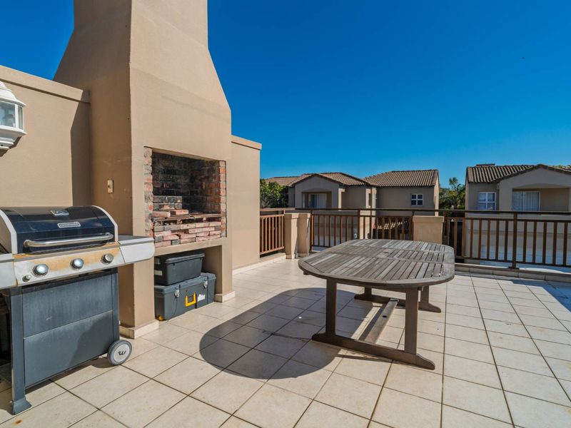 Spacious rooftop balcony featuring a built-in brick fireplace, tiled flooring, and protective railings, offering an ideal space for outdoor entertaining.