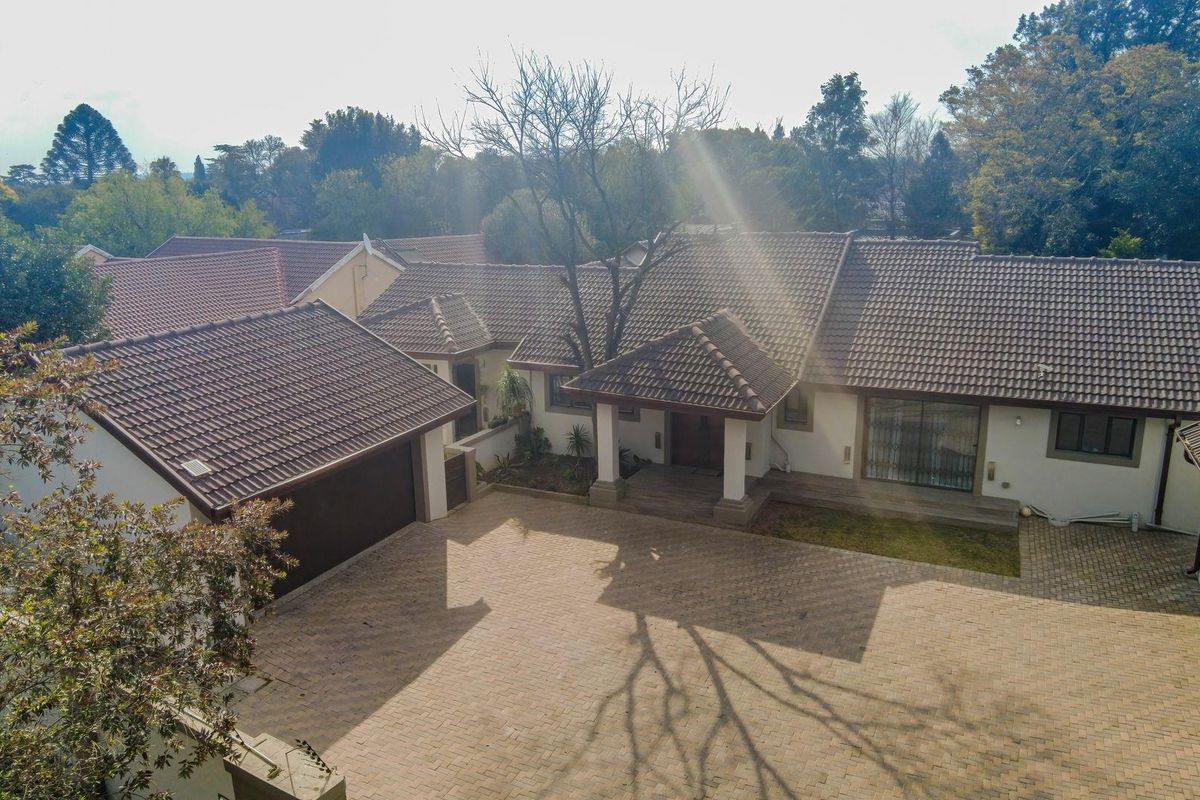 Aerial view of a residential property featuring a large paved driveway, double garage, and a covered entrance porch with a tiled roof.