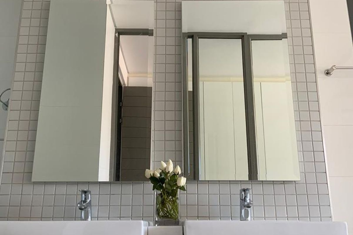 A modern bathroom featuring a double vanity with white basins, chrome fixtures, and a clean mosaic-tiled wall backdrop.