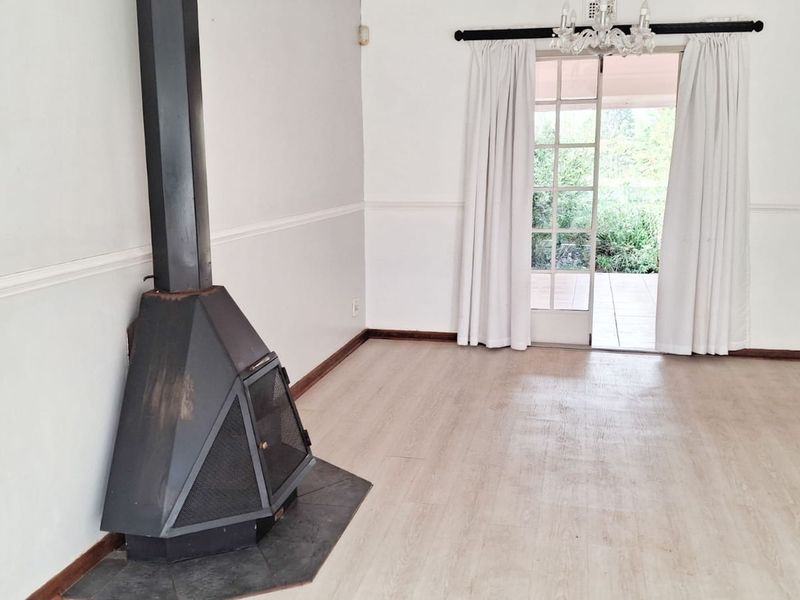 Spacious living room featuring a freestanding fireplace, laminate flooring, and direct access to the outdoor patio through classic french doors.