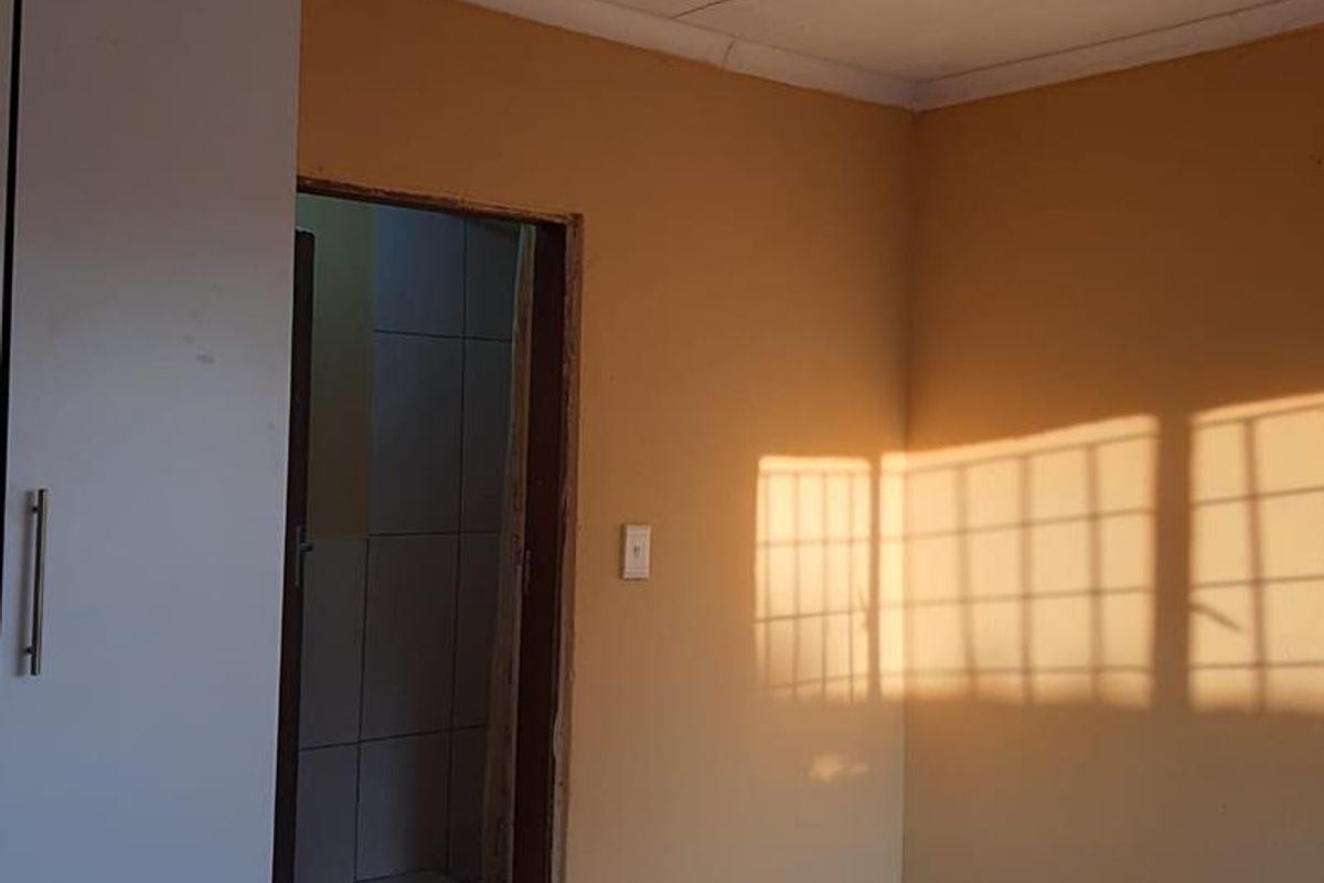 A simple bedroom featuring tiled flooring, built-in cabinetry, and direct access to an adjoining bathroom space.