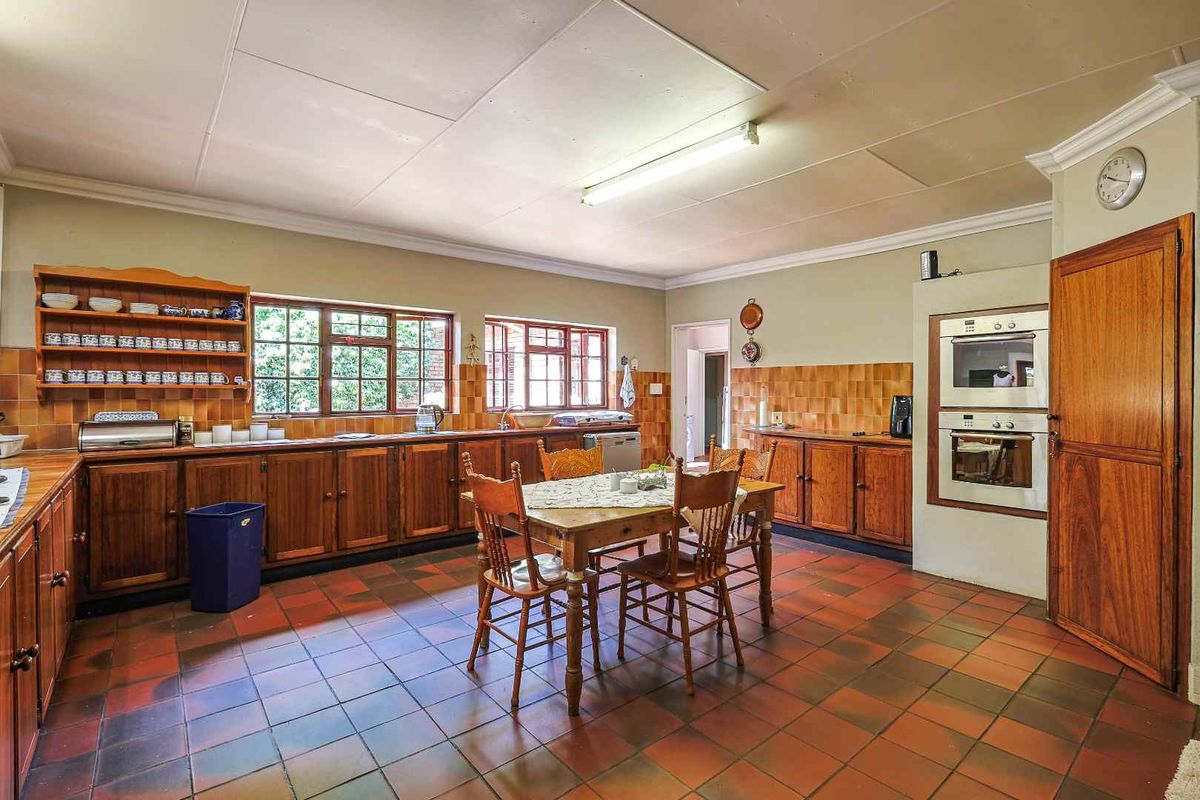 Spacious kitchen featuring traditional wooden cabinetry, built-in double oven, tiled flooring, and ample space for a dining table.