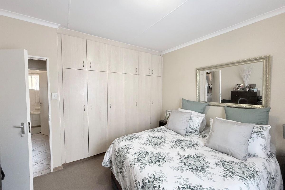 A well-maintained bedroom featuring extensive built-in cabinetry and an adjoining en-suite bathroom, offering practical storage and functional living space.