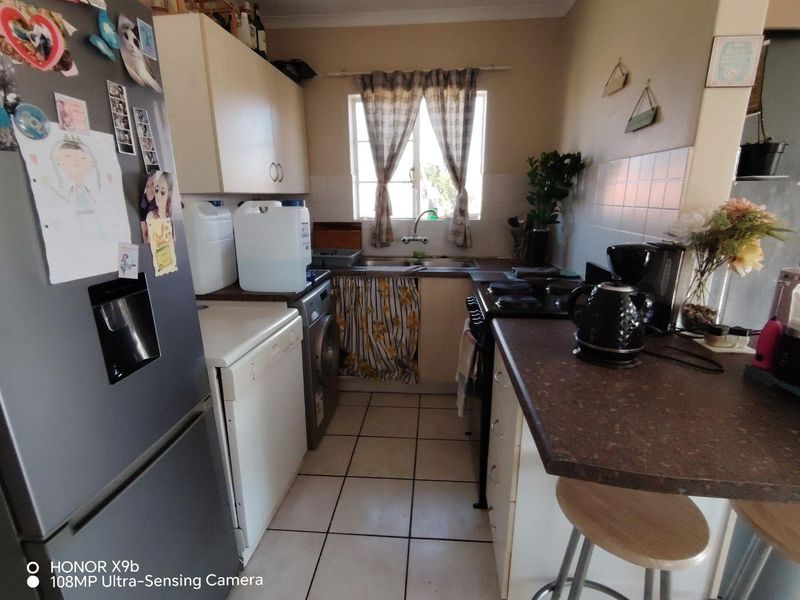 A compact kitchen featuring built-in cabinetry, laminate countertops, a double sink, and tiled flooring. The space offers functional layout potential for modern updates.