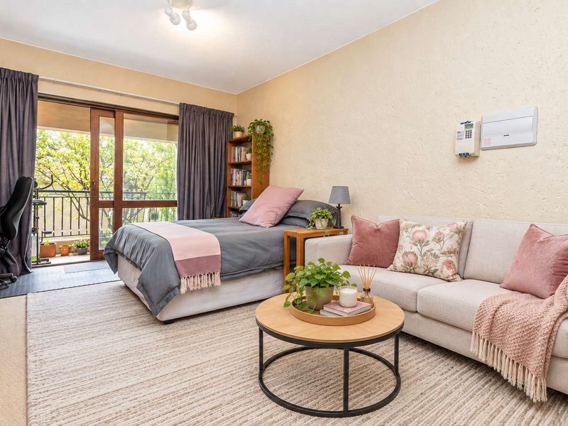 Open-plan studio apartment living area featuring textured walls, a sliding glass door leading to a balcony, and integrated electrical fixtures.