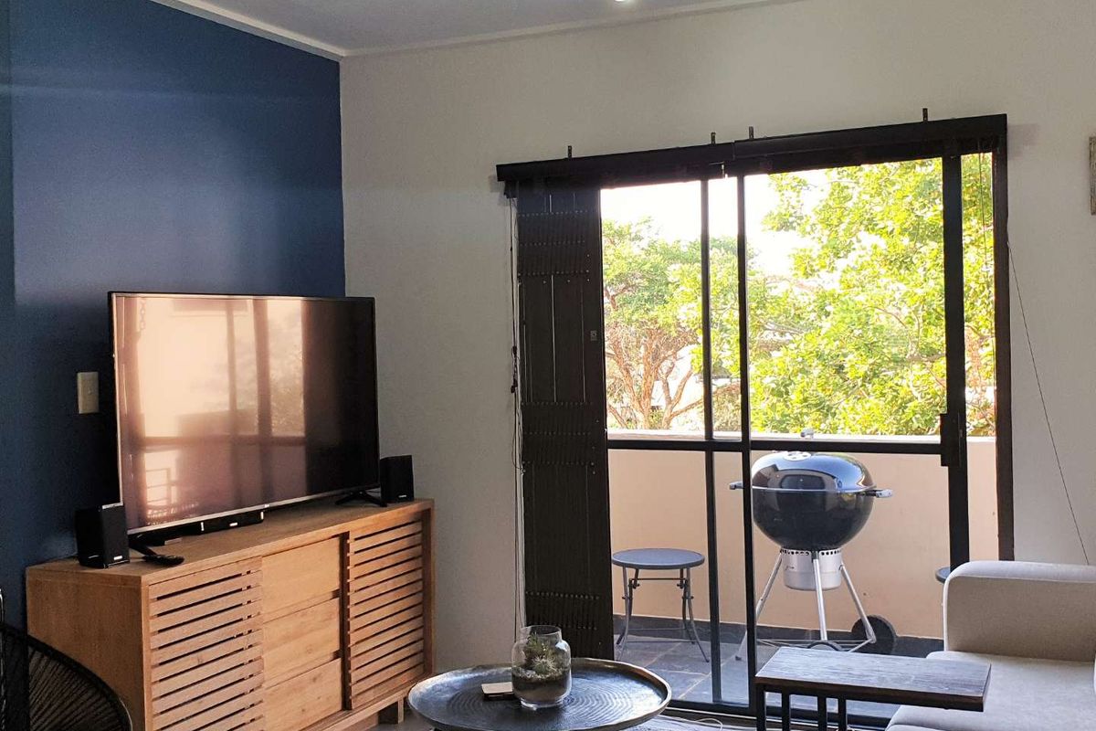 Living room featuring a blue accent wall and large sliding glass doors that open onto a private balcony.