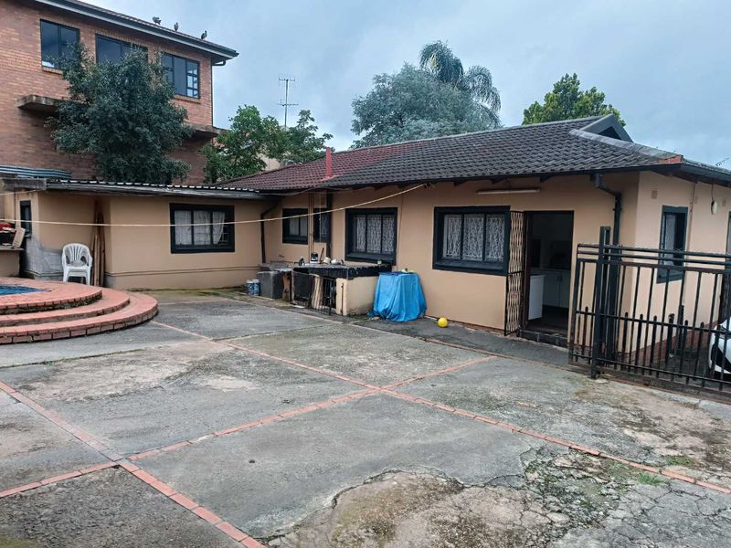 Rear exterior view of the property featuring a concrete patio area, swimming pool, and direct access to the main dwelling.