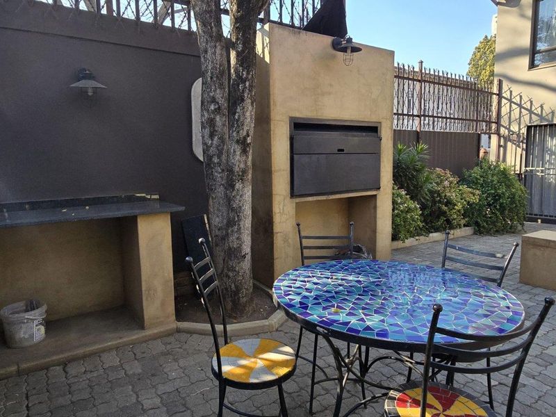 Outdoor patio area featuring a built-in braai, stone prep counter, and paved flooring, ideal for alfresco dining and entertaining.