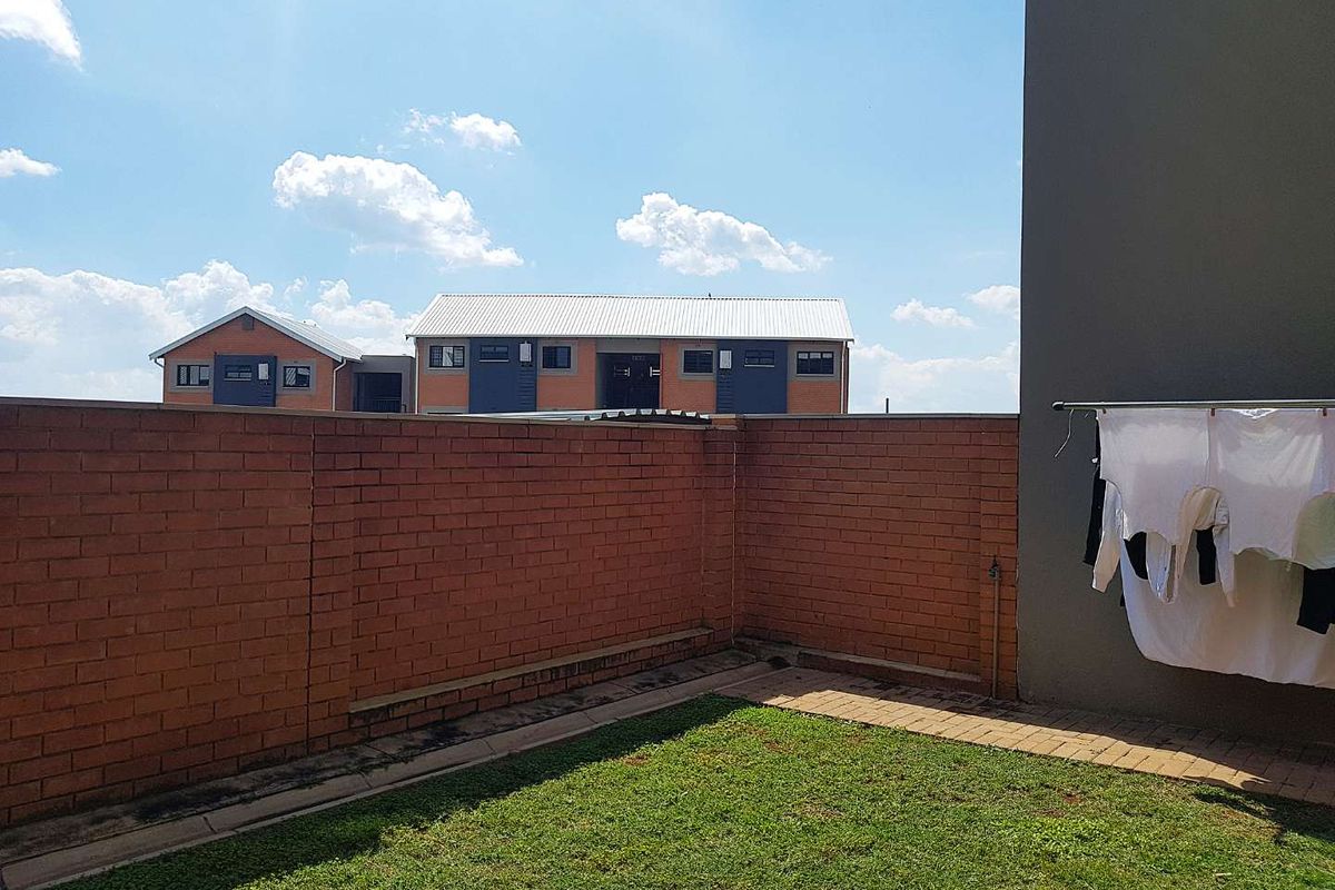 A private rear garden area featuring a brick boundary wall, a small lawn, and paved edging, providing a functional outdoor space.