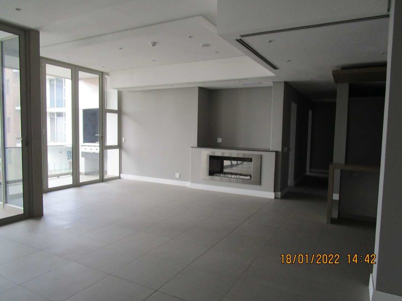 Spacious open-plan living area featuring large format floor tiles, a modern built-in fireplace, and floor-to-ceiling sliding doors leading to a balcony.