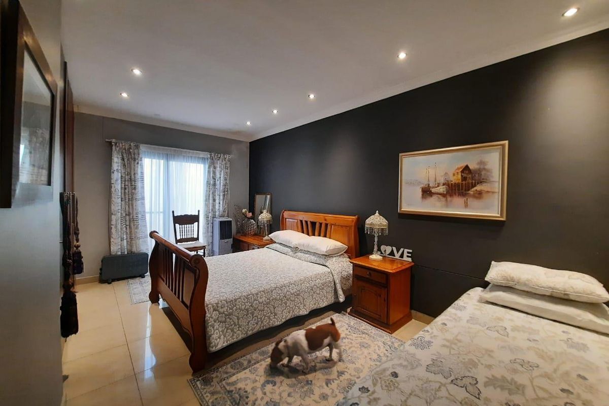 Spacious bedroom featuring tiled flooring, recessed downlighting, and a sliding glass door providing access to the exterior.