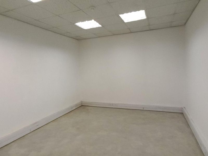 A vacant, neutral office space featuring a suspended ceiling with recessed lighting and perimeter trunking for electrical and data cabling.