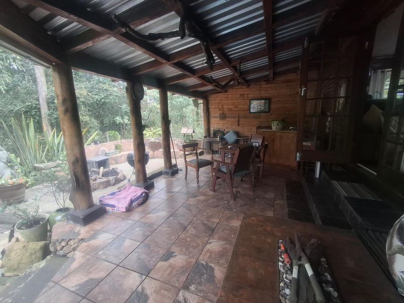 A covered outdoor patio featuring tiled flooring, timber support columns, and rustic timber wall cladding, providing a sheltered space for outdoor relaxation.