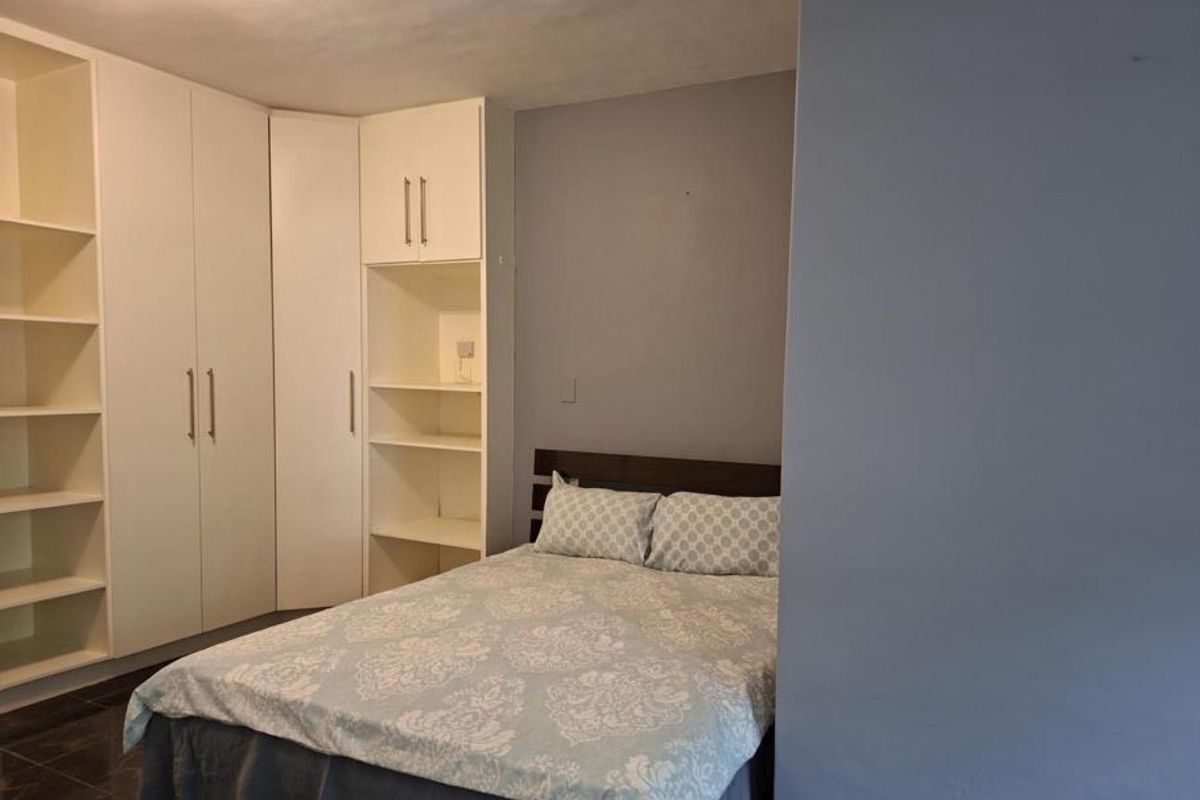 A bedroom featuring white built-in cupboards and integrated shelving units, providing ample storage space.